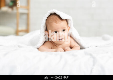 Die Entdeckung der Welt. Adorable Baby boy Kriechen auf Bett peeking unter abdeckt. Stockfoto