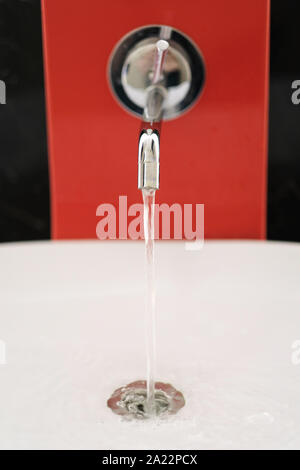 Wasser gießt aus einem offenen Tippen auf eine Wasserleitung zu einem Fayence Waschbecken Stockfoto