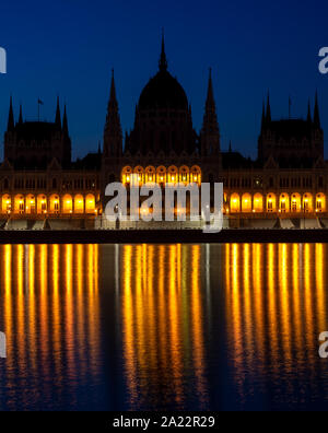 Parlament in Budapest, Ungarn. Berühmte Sehenswürdigkeiten, historische Gebäude. Blaue Stunde und Gelb leuchten, was in Donau wider. Stockfoto