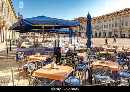 Ein Kellner serviert Kaffee in einem Restaurant auf der eleganten barocken Piazza San Carlo, einem der wichtigsten Plätze der Stadt, Turin, Italien Stockfoto