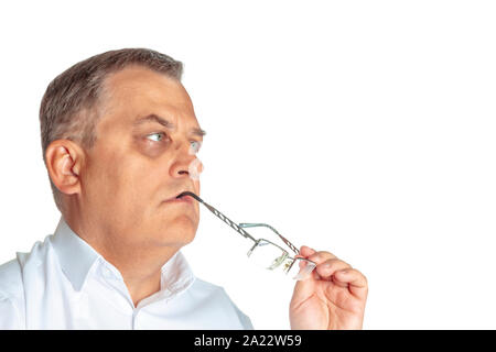 Der Mann ist nachdenklich und hält Gläser in seinen Mund. Auf einem weißen Hintergrund, aus der Nähe. Stockfoto