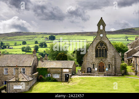 Grüne Weideflächen für Schafe mit Trockenmauern hinter Gemeindekirche in Reeth North Yorkshire England Stockfoto