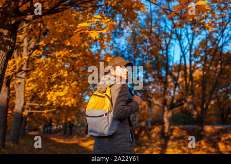 Tourist mit Rucksack wandern im Herbst Wald. Junge Frau reisen bei Sonnenuntergang Stockfoto