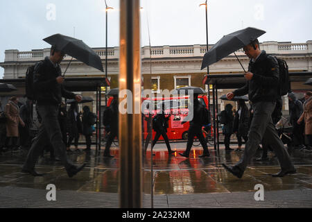 Pendler cross London Bridge, als Teile von Großbritannien für zwei weitere Tage von schweren Regengüsse strebe, vor einigen Schneefall und die Reste eines Hurrikans später diese Woche. Stockfoto