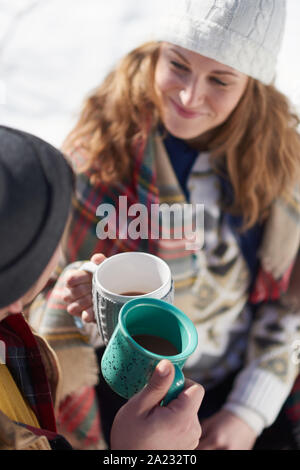 Paare von Mann und Frau in ein romantisches Picknick im Schnee im Winter, und Kuscheln unter einer Decke und einer Tasse Kakao zu Kee Stockfoto