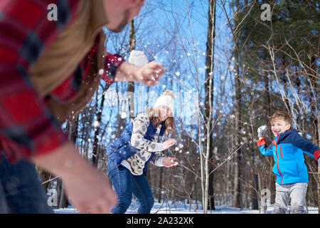 Familie von Mutter, Vater und junge Kind Spaß im Schnee im Winter und das Werfen mit Schneebällen während einer spielerischen Kampf Stockfoto