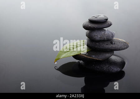 Zen Steine in ausgewogenen Haufen und grünen Blatt mit Wassertropfen Stockfoto