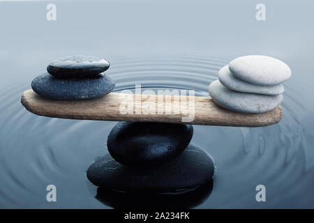 Sorgfältig schwarze und weiße zen Steine im Wasser ausgeglichen Stockfoto
