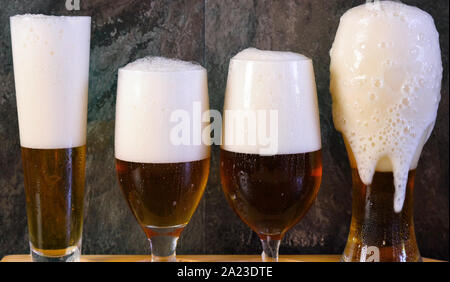 Bier zapfen in das traditionelle Bier Gläser auf schwarzem Schiefer bar Tisch, Bierverkostung auf Paddel aus Holz. Stockfoto