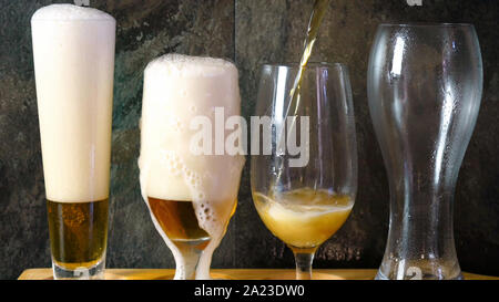 Bier zapfen in das traditionelle Bier Gläser auf schwarzem Schiefer bar Tisch, Bierverkostung auf Paddel aus Holz. Stockfoto