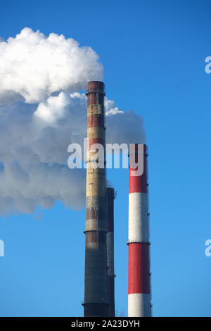 Weißer Rauch kommt aus Rohren gegen den blauen Himmel Stockfoto