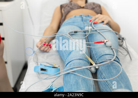 Der Patient liegt auf einer Couch in einem medizinischen Büro vor der Aufnahme eines Ekgs. Stockfoto