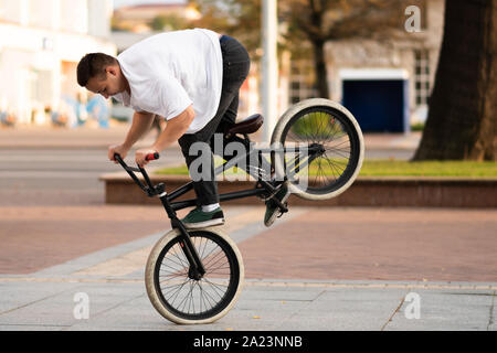 Der Kerl auf dem BMX Fahrrad führt einen Trick auf das Vorderrad. Stockfoto