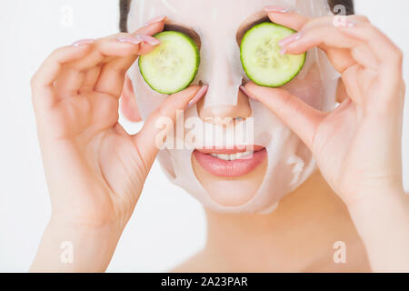 Schöne junge Frau in Ton Schlamm Maske auf das Gesicht, die Augen mit Scheiben Gurke. Stockfoto