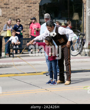 Javier Escamilla von Ballet Folklorico Nacional lehrt Seil spinnen Trick zu einem jungen Mädchen an zwei Flüssen, Wisconsin ethnischen Fest Street Fair. Stockfoto