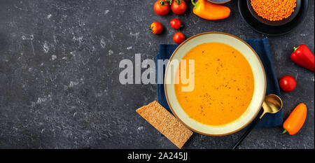 Veganer winter Creme Suppe mit roten Linsen auf schwarzem Hintergrund. Lange Banner. Platz kopieren Stockfoto