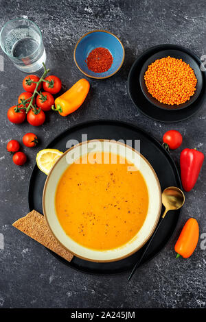 Vegan creme Suppe mit roten Linsen auf schwarzem Hintergrund. Vertikaler Dampfstoß Stockfoto