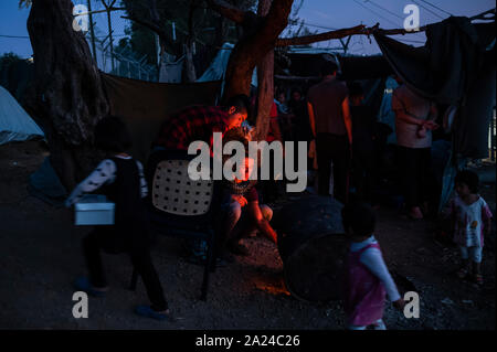 Athen, Griechenland. 26 Sep, 2019. Migranten versuchen, zu einem kleinen Brand in einem provisorischen Lager neben dem Moria Camp auf der Insel Lesbos zu warm. Credit: Angelos Tzortzinis/dpa/Alamy leben Nachrichten Stockfoto