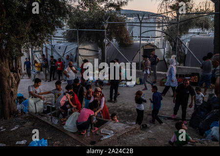 Athen, Griechenland. 26 Sep, 2019. Die Migranten stehen um ein Wasserloch und füllen Flaschen im Flüchtlingslager Moria auf der griechischen Insel Lesbos. Credit: Angelos Tzortzinis/dpa/Alamy leben Nachrichten Stockfoto