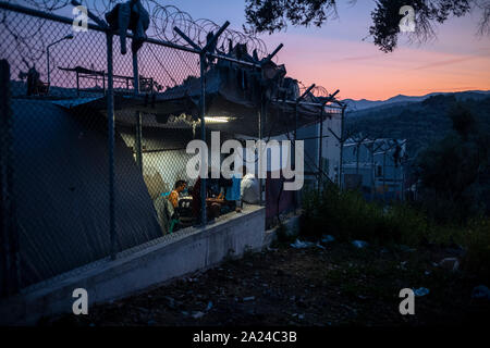 Athen, Griechenland. 26 Sep, 2019. Migranten sitzen in den Moria Camp auf der Insel Lesbos neben einem Stacheldrahtzaun. Credit: Angelos Tzortzinis/dpa/Alamy leben Nachrichten Stockfoto