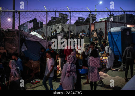 Athen, Griechenland. 26 Sep, 2019. Migranten verlassen die Moria Lager durch ein Loch im Zaun auf der Insel Lesbos. Fünf Inseln der östlichen Ägäis tragen die Hauptlast der Flüchtlinge Abkommen zwischen der EU und der Türkei. (Zu dpa: "Flüchtling Elend auf Lesbos: Bewohner und Migranten an der Grenze") Credit: Angelos Tzortzinis/dpa/Alamy leben Nachrichten Stockfoto