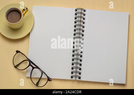 Leere Spirale Art Skizzenbuch mit einer Tasse Kaffee gegen strukturierte Krepppapier Stockfoto