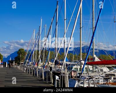 Segelboote vertäut am Genfer See im Hafen von Ouchy mit den Alpen im Hintergrund, Lausanne, Schweiz. Stockfoto