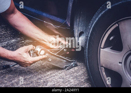 Mann anheben Auto mit Jack Schraube für Reifenwechsel der Reifenpanne Rad - Reifenwechsel oncept Stockfoto