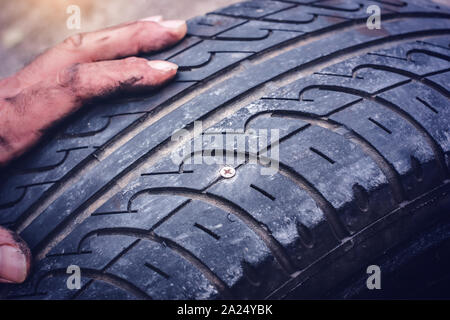 Hände auf flachen Reifen durchstochen mit einer Schraube closeup - Stockfoto