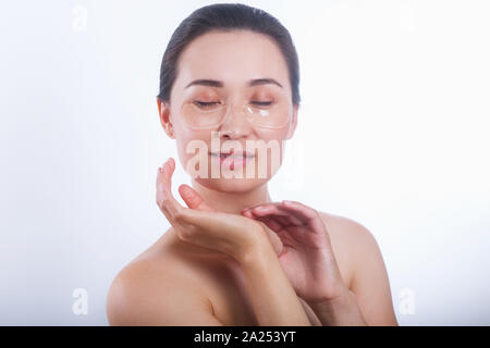 Asiatische Frau mit Kollagen Pads unter den Augen auf weißem Hintergrund. Stockfoto