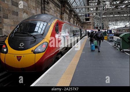 Fahrgäste fangen eine Jungfrau pendolino Zug nach London am Hauptbahnhof von Glasgow, Schottland Stockfoto