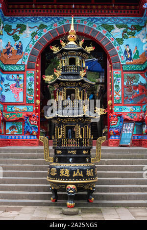 QingChengShan, Provinz Sichuan, China - 26. September 2019: Räuchergefäß vor einem bunten Temple Gate. Stockfoto