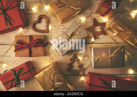 Verpackte Weihnachtsgeschenke mit Lichtern auf weißem Holz- Hintergrund Stockfoto