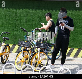 Junge Radfahrer Buch vermietet city Fahrräder in Peking mit Booking ihre Mobiltelefone. Stockfoto