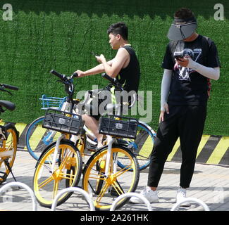 Junge Radfahrer Buch vermietet city Fahrräder in Peking mit Booking ihre Mobiltelefone. Stockfoto