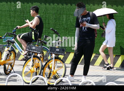 Junge Radfahrer Buch vermietet city Fahrräder in Peking mit Booking ihre Mobiltelefone. Stockfoto