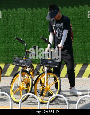 Junge Radfahrer Buch vermietet city Fahrräder in Peking mit Booking ihre Mobiltelefone. Stockfoto