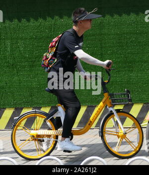 Junge Radfahrer Buch vermietet city Fahrräder in Peking mit Booking ihre Mobiltelefone. Stockfoto