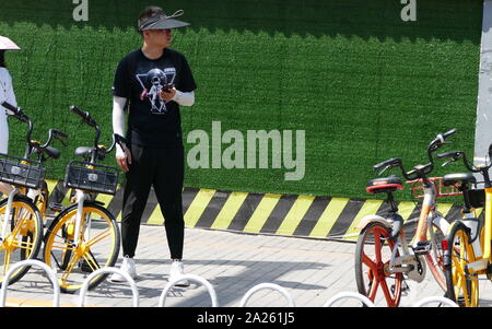 Junge Radfahrer Buch vermietet city Fahrräder in Peking mit Booking ihre Mobiltelefone. Stockfoto