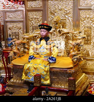 Kind nachgespielt, die Rolle der letzte Kaiser von China Pu Yi auf einer Replik des Drachen Thron sitzt. Als der Drache war das Emblem der Göttlichen imperiale Macht, den Thron des Kaisers, der als ein lebender Gott, wurde als die Drachen Thron bekannt Stockfoto