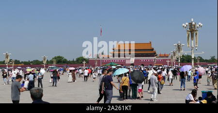Massen von chinesischen Touristen besuchen Sie die Verbotene Stadt in Peking, China. Tragen viele UV-Schirme zum Schutz vor der gnadenlosen Sonne einmal Sie erreichen. Da sie den Platz des Himmlischen Friedens Überwachungskameras Film die Massen. Stockfoto