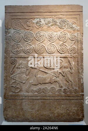 Grabkunst Stele aus porösem Stein, mit Relief chariot Szene. Die Spiralen im oberen Panel kann Wellen darstellen, so dass die Lage an der Küste der Szene im unteren Bereich. Die ständigen Wagenlenker zieht am Zügel, während eine zweite Figur, wer hält eine Waffe (möglicherweise ein Schwert) in seiner linken Hand und vor dem Wagen gezeigt wird. Mykene, Grave Kreis ein, Schwere V, 16 Cent. BC. Stockfoto