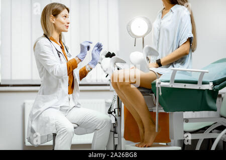 Frauenarzt vorbereiten für ein Prüfverfahren für eine schwangere Frau sitzt auf einem gynäkologischen Stuhl im Büro Stockfoto