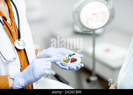 Arzt Holding pillbox mit einigen Medizin in der gynäkologischen Büro, Nahaufnahme auf die Hände und Pillen Stockfoto