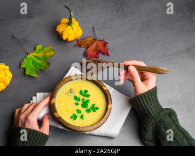 Weibliche Hände halten eine Schüssel mit Kürbis und geröstete Kichererbsen Suppe. Top View Stockfoto