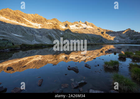 Peaks spiegelt sich auf alpinen See. Reichenspitzgruppe. Reichenspitze Peak. Sunrise Sonnenlicht auf Gipfel und Gletscher. Nationalpark Hohe Tauern Nationalpark. Stockfoto