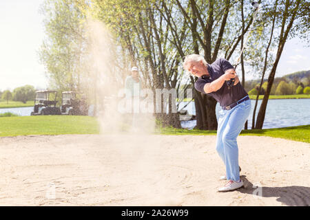 Ältere Golf player Pitching von Bunker. Stockfoto