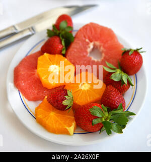 Erdbeeren und Orangenscheiben und Grapefruit auf einem Teller Stockfoto