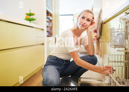Hausfrau an der Spülmaschine in der Küche denkt über Rollen Verteilung Stockfoto