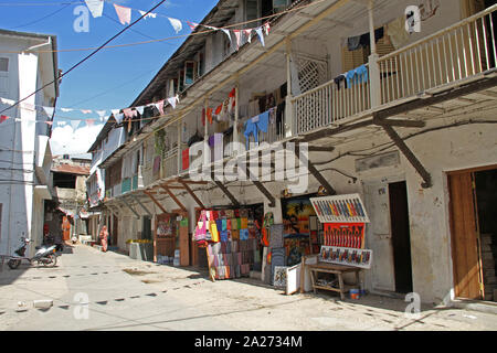 Lokale muslimische Frau zu Fuß in der Straße Gasse mit offenen Marktständen, Stone Town, Sansibar, Tansania. Stockfoto